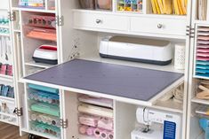 a sewing machine sitting on top of a table next to shelves filled with craft supplies