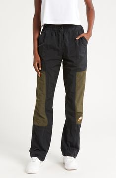 Front-zip cuffs lend styling versatility to lightweight track pants with deep front pockets and a signature logo at the calf. 31" inseam; 18" leg opening; 13 1/2" front rise; 16" back rise (size Medium) Drawcord-toggle waist Front slant pockets 100% nylon Machine wash, tumble dry Imported Nordstrom x Nike: A curated lifestyle destination where fashion is the ultimate sport Sports Pants With Zip Fly In Black, Nike Nylon Pants For Streetwear, Nike Nylon Streetwear Pants, Black Sporty Pants With Zip Fly, Sporty Black Pants With Zip Fly, Black Sporty Parachute Pants, Sporty Black Pants With Functional Pockets, Black Cargo Pants With Hip Pockets, Black Tapered Leg Cargo Pants For Outdoor Activities