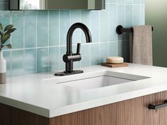 a bathroom sink with a black faucet next to a mirror and soap dispenser