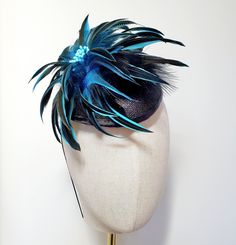 Little Hats for Grand Occasions. Customer information and sizing. Black pillbox style hatinator base. A spray of black and turquoise feathers sit on top in a flower style.  Perfect pillbox hatinator for weddings, special events, racing or a grand occasion. Embellishments, feathers, buttons and brooches are lovingly sourced for unique individual pieces. Hat is 17cm by 14cm and dispatched in a box. Millinery elastic has been attached for ease of fixing in place to the head.  Handmade in the UK. No two designs are the same. Please message me to discuss any personnal requirements. Return and exchanges except within 14 days. Please read the full details in the FAQS. Many more designs on the shop. Company Christmas Party, Holiday Hats, Wedding Fascinators, Pill Boxes, Black Feathers, Beautiful Hats, Flower Fashion, Wedding Guest, Wedding Hair Accessories