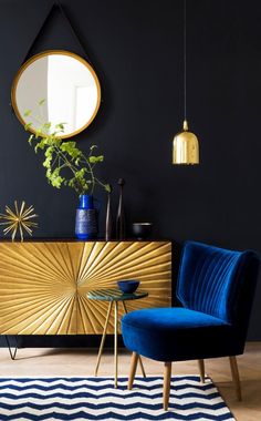 a blue chair sitting in front of a gold sideboard with a mirror on it