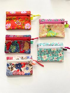 four small zippered purses lined up on a white surface, each with different designs and colors