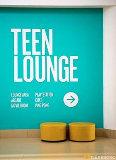 two yellow stools in front of a turquoise wall with the words teen lounge on it