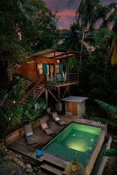 an outdoor swimming pool surrounded by trees and plants at dusk with people sitting on the deck