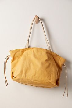 Easy and relaxed, this chic tote bag is featured in a slouchy style and canvas fabrication, with leather details for an edgy touch. **Features:** Tote style, slouchy design, canvas fabrication, leather tie sides, top handles, cinched closure, interior zip pocket **Why We | Daybreaker Tote Bag by FP Collection at Free People in Yellow Chic Weekend Shoulder Bag With Adjustable Strap, Chic Shoulder Bag With Adjustable Strap For Weekend, Summer Weekender Bag With Leather Handles, Weekend Shoulder Bag With Canvas Lining, Chic Tote Bag For Weekend, Chic Weekend Tote Bag, Canvas Shoulder Bag With Leather Handles For Weekend, Casual Canvas Bag With Leather Handles For Weekend, Cotton Hobo Bag With Adjustable Strap For Shopping