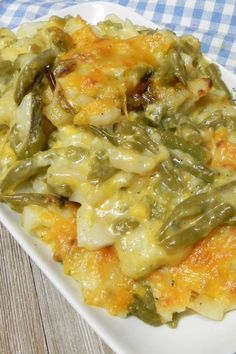 a white plate topped with green beans and cheese covered casserole on top of a blue checkered table cloth