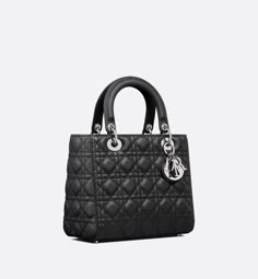 The Lady Dior bag epitomizes the House's vision of elegance and beauty. Sleek and refined, the timeless style is crafted in black grained calfskin with Cannage stitching, creating the instantly recognizable quilted texture. Silver-finish metal D.I.O.R. charms offer elegant appeal. Featuring a thin removable leather shoulder strap, the medium Lady Dior bag can be carried by hand or worn crossbody.. Lady Dior Bag Black, Dior And I, Icon Shoes, Dior Book Tote, Small Lady, Christian Dior Couture, Dior Couture, Backpack Tote Bag, Lady Dior Bag