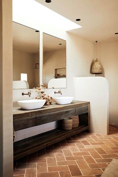 two white sinks sitting on top of a wooden counter next to a wall mounted mirror