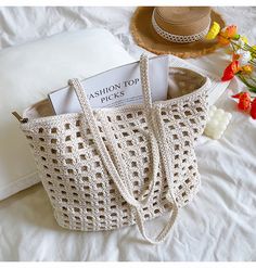 a white crocheted bag sitting on top of a bed next to a pillow