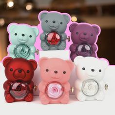 four different colored teddy bears sitting next to each other on top of a white table