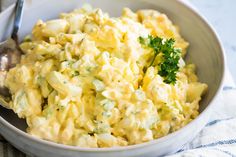 a white bowl filled with eggs and broccoli on top of a table next to a spoon