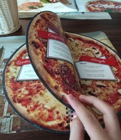 someone is holding up a pizza with two slices taken out of it on a plate