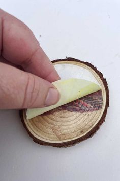 a hand is holding an apple slice over a piece of wood