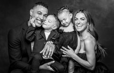 a family poses for a black and white photo in front of a dark background with their child