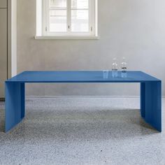 a blue table sitting in front of a window with two glasses on top of it