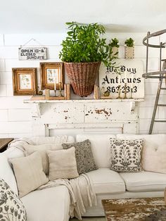 a living room filled with white furniture and lots of greenery on top of it