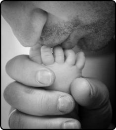 a black and white photo of a man holding a baby's hand