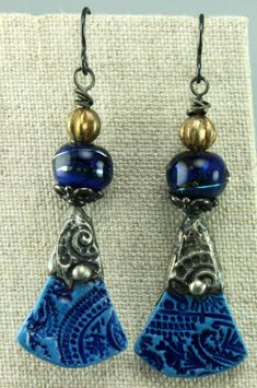 #1043, Striking Blue Silver Tinned Ceramic Charms by Sasha Crow are paired with Patricia Ritchie Glass Beads and Czech Glass Melon Beads. Dark Bead Caps & Black Niobium earwires finish off these earrings. The earrings are 2.3 long from the top of the earwire, 2 inches from the top of the earrings, and .5 inches wide. Each earring is a very light weight at .1 ounce. Please treat Chris Kaitlyn Jewelry like Wearable Art by putting them on after applying hair sprays, perfume, chemicals, soaps, water, etc. Packaging and Shipping to the United States is included in the price. "Chris Kaitlyn's Jewelry is fabulous. I buy my clothes to match the earrings that I purchase from Chris's creative collection!" Sage Vanzandt, Olympia, Washington. Read the About section to learn more about Chris Kaitlyn Je Artisan Blue Earrings, Adjustable Blue Bohemian Earrings, Blue Bohemian Dangle Earrings, Handmade Artisan Blue Earrings, Artisan Handmade Blue Earrings, Artisan Blue Drop Earrings, Bohemian Blue Nickel-free Earrings, Blue Bohemian Earrings For Pierced Ears, Artisan Blue Nickel-free Earrings