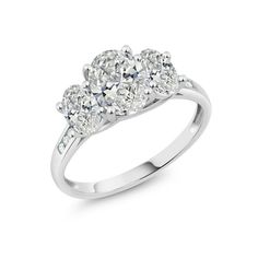 three stone diamond ring in white gold with diamonds on the shoulders and sides, set against a plain background