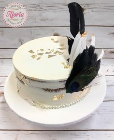 a white cake with gold and black feathers on top