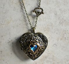 "Music box pendant. This heart shaped music box pendant is inspired by the gorgeous music box pendants of era's gone by. Music box is pill box size, please look at the dimensions for exact size. A perfect bronze heart locket has been adorned with stacked layers of filigree and a delicate blue crystal heart nestled inside a bronze floral heat. The filigree stacks and and bronze floral heart have been finished with resin to preserve the beauty of this pendant. The music box winds from a key on the Blue Antique Jewelry With Antique Finish, Blue Antique Finish Jewelry For Gift, Blue Antique Finish Jewelry Gift, Antique Gold Heart Locket Necklace Gift, Vintage Blue Keepsake Jewelry, Elegant Blue Locket Necklace Gift, Vintage Blue Locket Necklace For Gift, Music Box Locket, Heart Shaped Locket