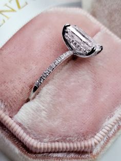 a diamond ring sitting on top of a pink velvet case