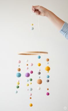 a hand holding a mobile with balls hanging from it