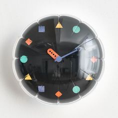 a black clock with colorful shapes on it's face and numbers in the middle