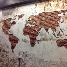 an old world map is on the side of a building in front of a brick wall