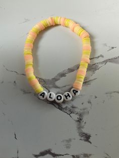 "this is a pink, bright yellow, and light yellow. clay beaded braclet made by me! It says \"aloha\" on it, Which means hello!" Colorful Beaded Yellow Bracelets For Vacation, Yellow Beaded Bracelets For Vacation, Adjustable Yellow Friendship Bracelets With Letter Beads, Fun Yellow Beaded Bracelets For Beach, Yellow Beaded Bracelet For Vacation, Yellow Bracelets With Round Beads For Vacation, Summer Yellow Bracelets With Letter Beads, Yellow Letter Beads Bracelets For Summer, Yellow Letter Beads Jewelry For Beach