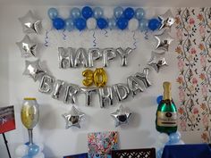 a birthday party with balloons and streamers on the wall, wine bottle and champagne