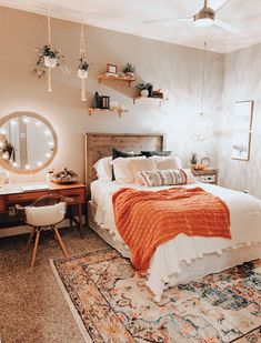 a bed room with a neatly made bed next to a desk and mirror on the wall