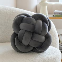 a gray knot pillow sitting on top of a white chair