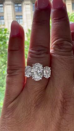 a woman's hand with three stone engagement ring on top of her left hand