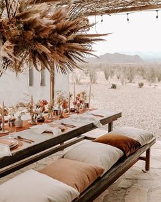 a long table set with place settings and flowers on it for an outdoor dinner party