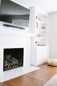 a flat screen tv mounted above a fire place in a living room with white walls