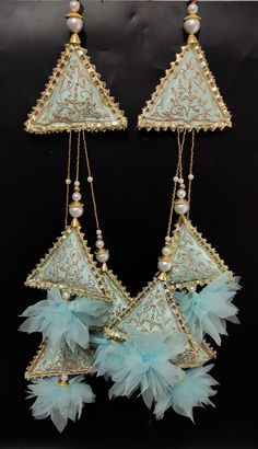 two pieces of jewelry are hanging on a black surface with pearls and beads around them