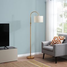 a living room with a couch, chair and television on the stand in front of a window