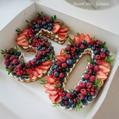 a cake shaped like the number 50 decorated with berries and strawberries