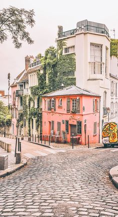 an orange building with graffiti on it in the middle of a cobblestone street