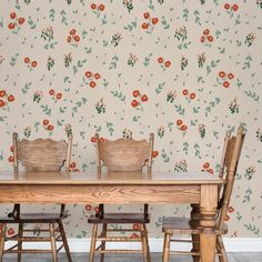 a wooden table with four chairs in front of a floral wallpaper