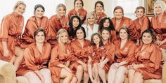 a group of women sitting next to each other in orange robes on top of a couch