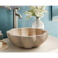 a bathroom sink with three bowls on top of it and flowers in the vase next to it