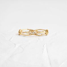 an image of a gold ring with diamonds on the top and bottom, sitting on a white surface