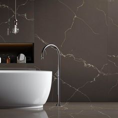 a white bath tub sitting next to a wall mounted faucet in a bathroom