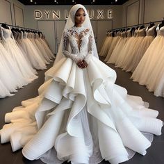 a woman is standing in front of wedding gowns at a bridal shop wearing a long sleeved dress with ruffled layers