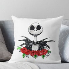 a white pillow with a black and red skeleton on it's face, surrounded by roses