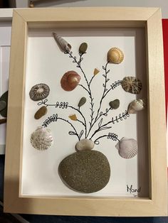 there is a framed picture with sea shells on it and a tree made out of seashells