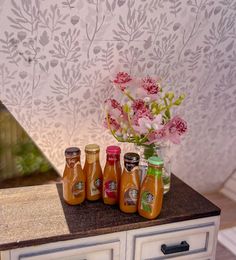 there are four jars on the counter with flowers in them and one is filled with honey