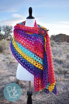 a colorful crocheted shawl is on a mannequin in the desert